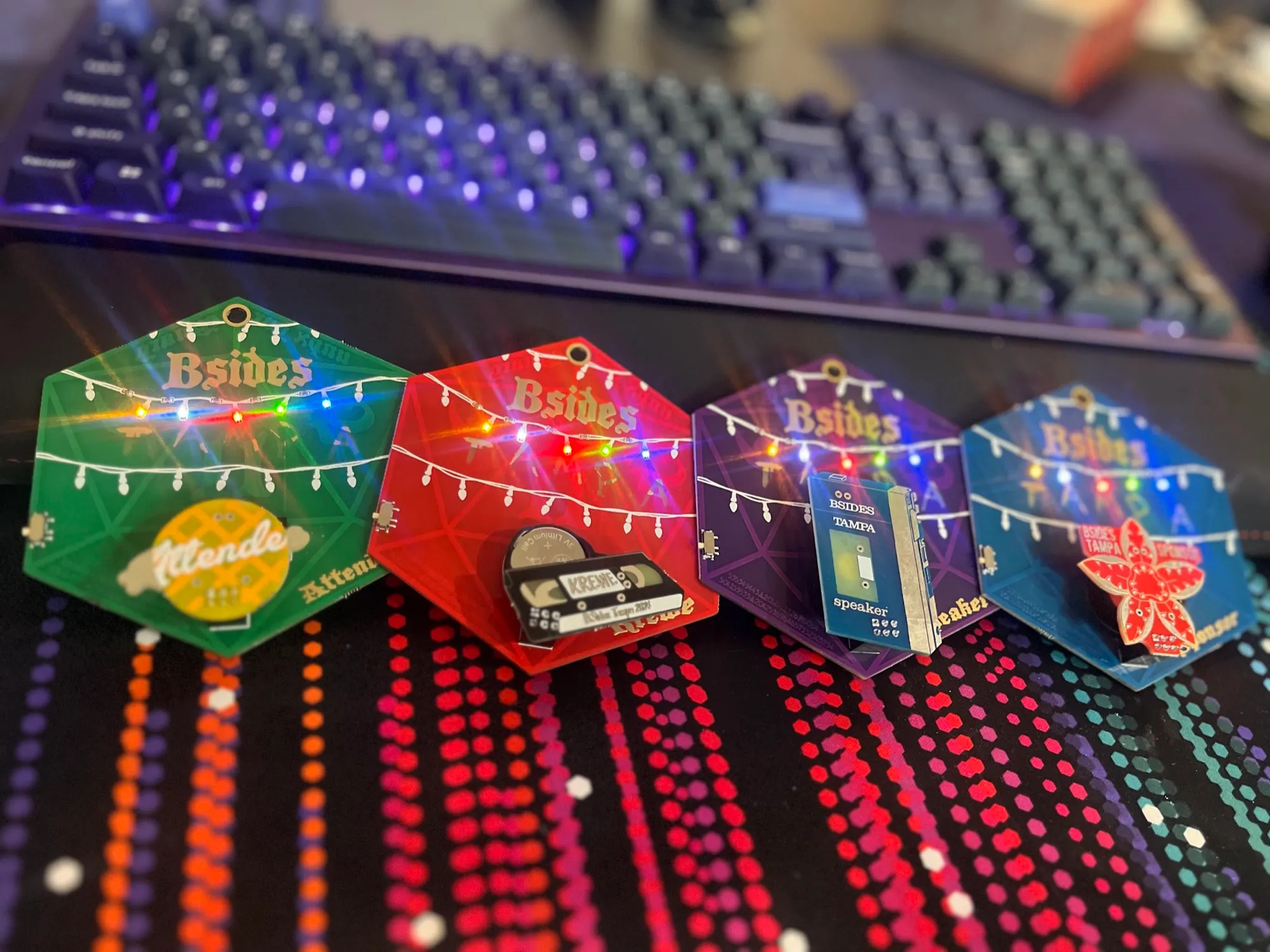 BSides Tampa badges from multiple years, lit up with colorful LEDs